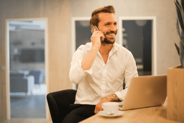 Man smiling on phone with laptop